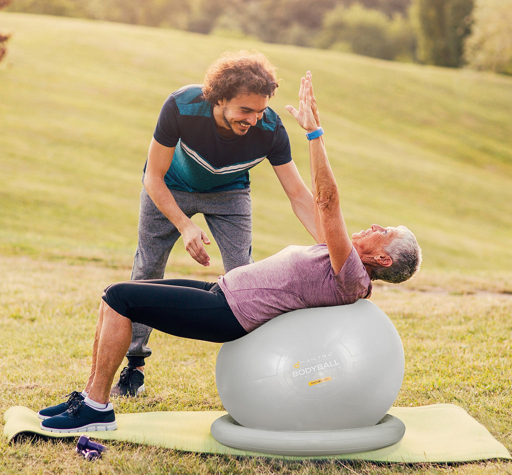 a gym trainer using the exercise ball on his student
